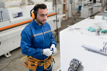 Handsome carpenter in safety blue uniform control machine of monitor button at factory	