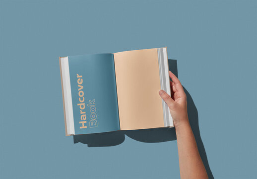Hand Holding an Open Hardcover Book Mockup With Custom Background