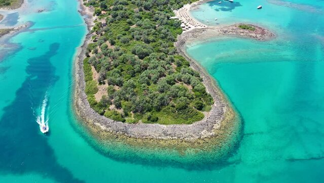 Aerial drone video of small boat cruising in Caribbean tropical rocky bay with turquoise - crystal clear sea