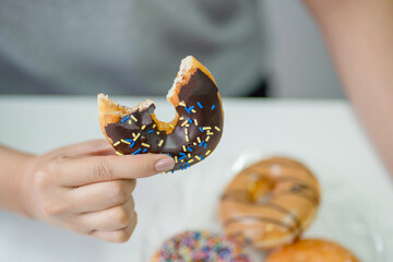 Close up of woman hand holding donuts. Junk food and eating concept.