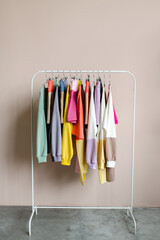 Rack with stylish women's clothes near light wall. Bright clothes on a hanger. High quality photo