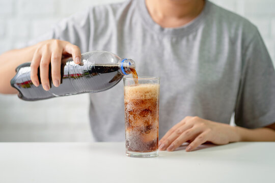 Young Woman Pouring Cold Cola Soft Drink Soda From A Bottle Into A Glass In Her Hand. Health Care, Healthy Diet Lifestyle Concept.