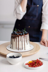 The confectioner decorates a delicious beautiful cake with berries. High quality photo