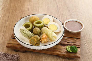 Siomay Bandung (Shumay) or steamed dumplings with boiled egg, tofu, potatoes and cabbage roll. Indonesian traditional street food with peanut sauce and soy sauce, and green lime.
