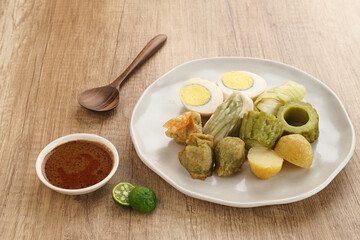 Siomay Bandung (Shumay) or steamed dumplings with boiled egg, tofu, potatoes and cabbage roll. Indonesian traditional street food with peanut sauce and soy sauce, and green lime.
