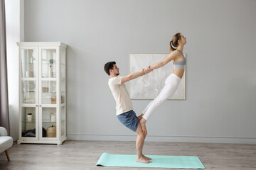 The couple is doing yoga in the studio. Partner support. copy space. High quality photo