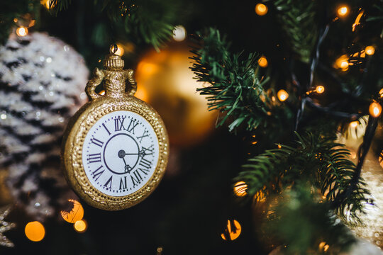 Picture of decorated New Year or Christmas tree with garlands and baubles. Decoration in form of clock symbolizes starting new year. Holidays, celebration, winter concept.