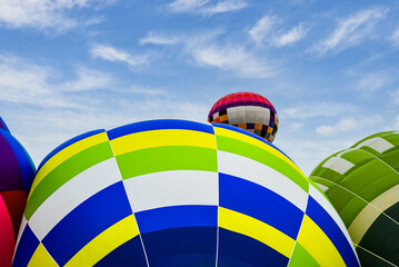 Colorful hot air balloon flying over blue sky with white clouds	
