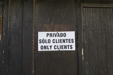 Privado. Solo clientes. Only Clients. (Privé. Reservé aux clients) Pancarte en espagnol et anglais sur une porte.