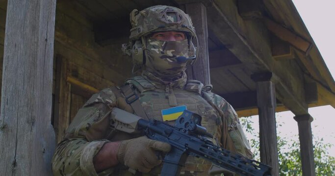 Portrait of Ukrainian soldier   wearing balaclava and protective helmet and uniform with chevron  blue and yellow flag of Ukraine . Ukrainian army, defenders in the Ukrainian-Russian war, going to vic