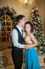 Young couple decorating christmas tree in room