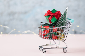 Shopping cart with Christmas presents and Christmas tree. Christmas and New year shopping concept.