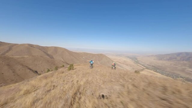 Cross motorbike downhill sport man extreme racing desert crag summit sky sun aerial view. FPV drone shot adventure race biking competition rocky terrain valley active lifestyle outdoor exercising 4k