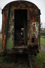 an old rusty shabby train carriage without windows and doors with peeling green paint stands on the grass