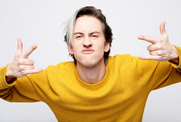 Stylish fashionable young man wearing yellow sweater dancing to the music