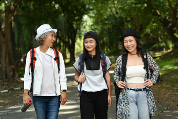 Image of two smiling middle aged women and teenage girl walking through public park together