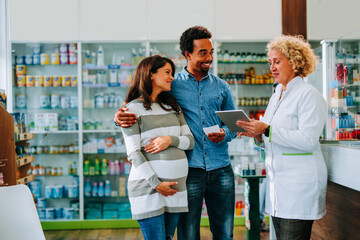 Pharmacist serving diverse couple in pharmacy.