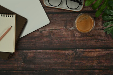 Cup of coffee, notepad, eyeglasses and houseplant on wooden table. Top view with copy space for your text