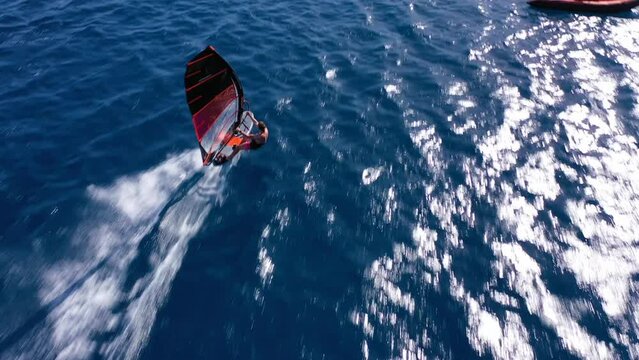 Aerial drone video of wind surfer cruising in high speed in tropical wavy open ocean beach with deep blue sea