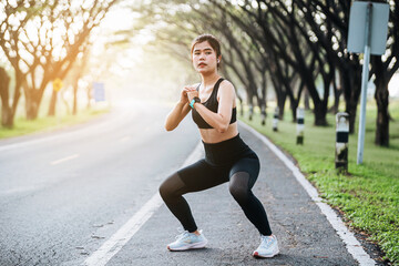 Beautiful fitness asian woman doing squat sit up exercise workout at sport stadium. Attractive female warming up body training wearing sportswear. Healthy and active lifestyle concept.