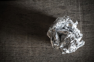 Foil ball on wooden background. Picture dark tone.