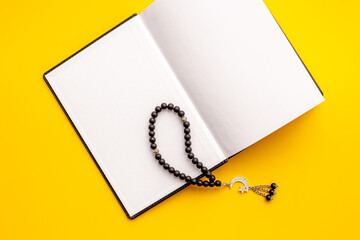 Koran book and black Muslim rosary with silver crescent moon