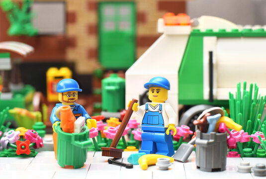 Lego minifigure of cleaning service is removing a garbage in trash cans closed up isolated on white background. Editorial illustrative image of popular toy.