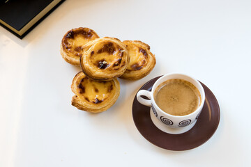 Pasteis de nata, traditional sweet of Portuguese cuisine. Small crunchy puff pastry pies and a cream made with eggs. Often tasted and accompanied with coffee. Isolated on white background, copy space.