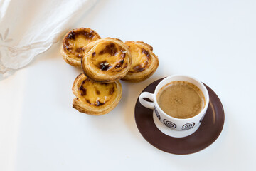 Pasteis de nata, traditional sweet of Portuguese cuisine. Small crunchy puff pastry pies and a cream made with eggs. Often tasted and accompanied with coffee. Isolated on white background, copy space.