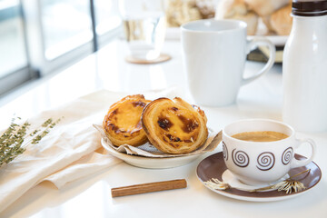 Pasteis de nata, traditional sweet of Portuguese cuisine. Small crunchy puff pastry pies and a cream made with eggs. Often tasted and accompanied with coffee. Breakfast table set.