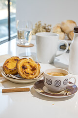 Pasteis de nata, traditional sweet of Portuguese cuisine. Small crunchy puff pastry pies and a cream made with eggs. Often tasted and accompanied with coffee. Breakfast table set.