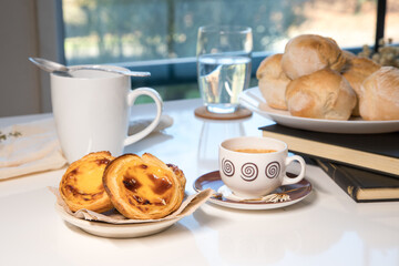 Pasteis de nata, traditional sweet of Portuguese cuisine. Small crunchy puff pastry pies and a cream made with eggs. Often tasted and accompanied with coffee. Breakfast table set. 