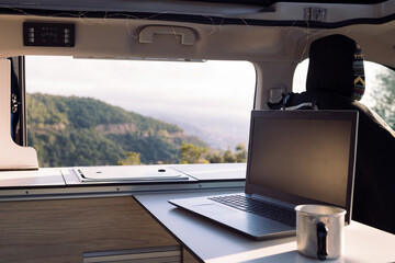 interior table of a camper van with a laptop and a mug, concept of freedom and digital nomad...