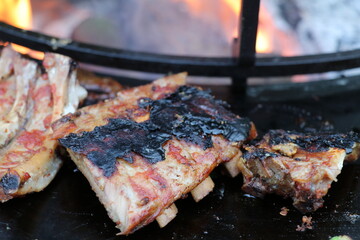 barbecued ribs next to the fire with the skin burnt black