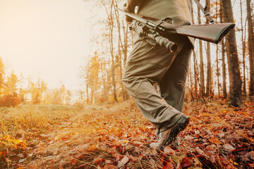 Autumn hunting season, hunter with rifle looking out for some wild animal in a wood or forest, outdoor sports concept