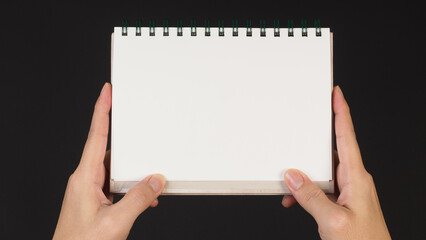 Obraz premium Hand is holding notebook isolated on black background