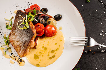 Tasty grilled dorada fish with boiled vegetables and sauce on wooden background