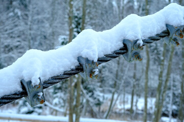 The cable ties of the pedestrian bridge are screwed together with screws. snowy winter