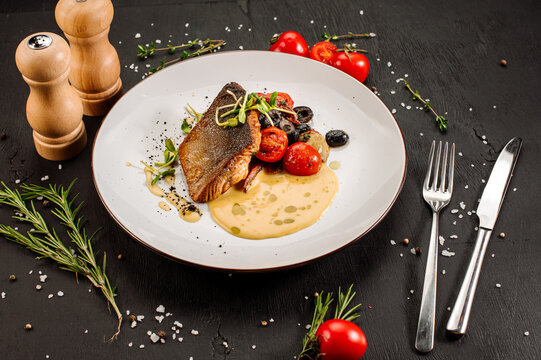 Tasty grilled dorada fish with boiled vegetables and sauce on wooden background