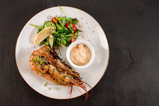 Dish of big king shrimps with herbs on wooden background