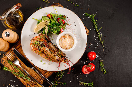 Dish of big king shrimps with herbs on wooden background