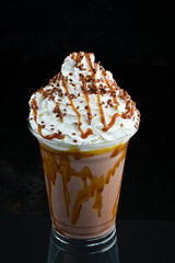 Caramel milkshake in a plastic cup. on a black background. Free space for text.