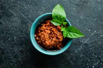 Pesto sauce with sun-dried tomatoes in a bowl. Traditional Italian sauce. On a concrete background.