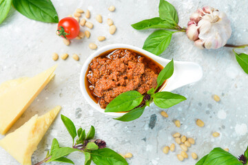 Preparation of traditional Italian pesto sauce with dried tomatoes. Ingredients: basil, parmesan, pine nuts, tomatoes, spices. On a concrete background.