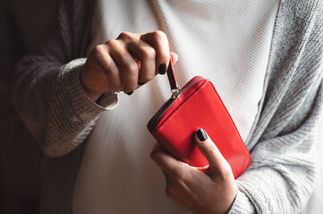 Beautiful black painted nails on woman's hand holding a red wallet. Winter manicure.