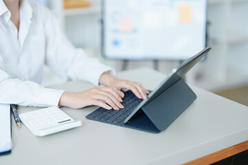 Portrait of a thoughtful Asian businesswoman looking at financial statements and making marketing plans using a computer on her desk