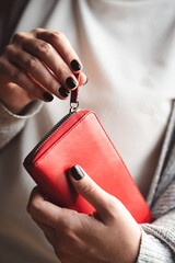 Beautiful black painted nails on woman's hand holding a red wallet. Winter manicure.