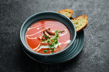 Tomato soup with bacon, onion and cream. Mexican cuisine. On a black stone background.