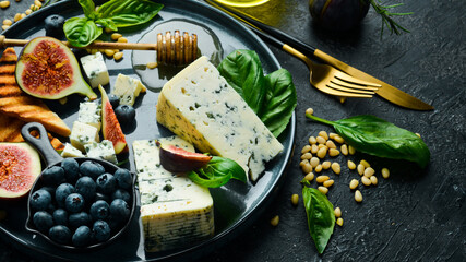 Traditional blue cheese, figs, blueberries and honey in a plate. On a concrete background. Side view.