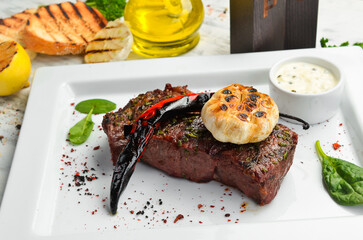 Grilled ribeye beef steak, herbs and spices on a plate. Top view.
